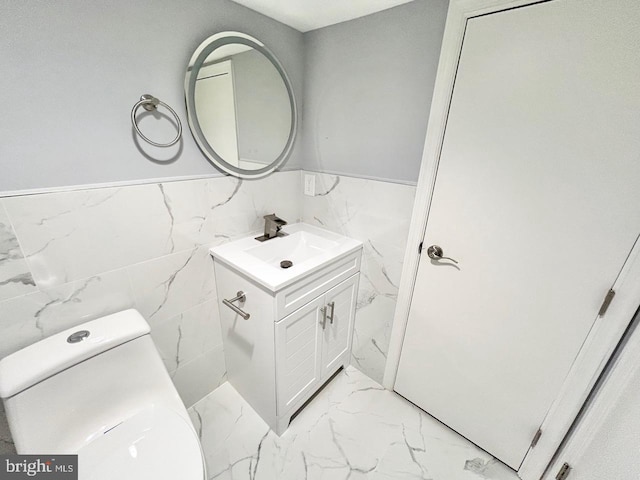 bathroom with vanity, toilet, and tile walls