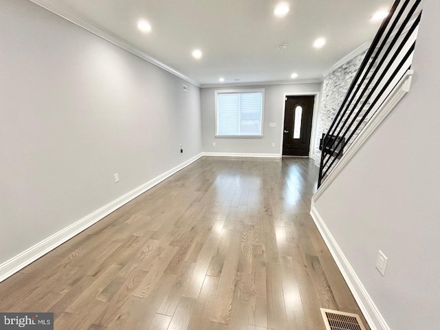 entryway with wood-type flooring and ornamental molding