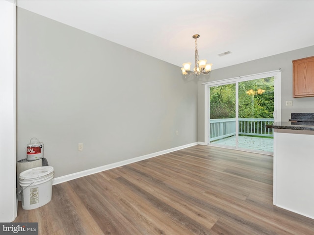 unfurnished dining area with a chandelier and hardwood / wood-style flooring