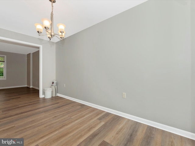 unfurnished room featuring a chandelier and hardwood / wood-style flooring