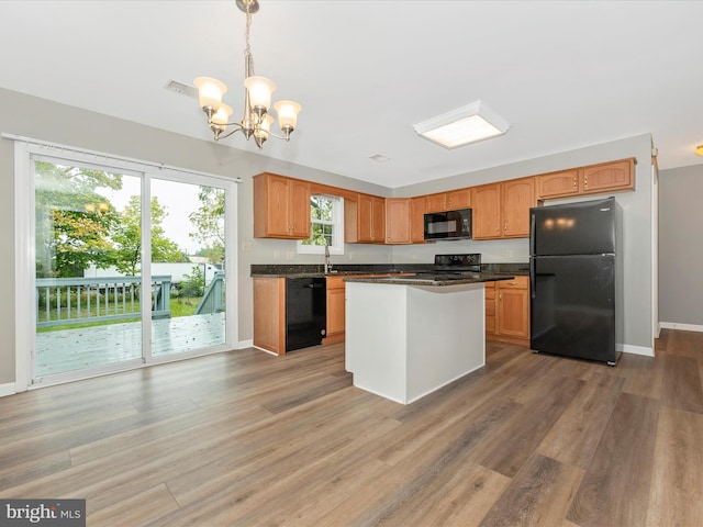 kitchen featuring wood-type flooring, decorative light fixtures, black appliances, and a wealth of natural light