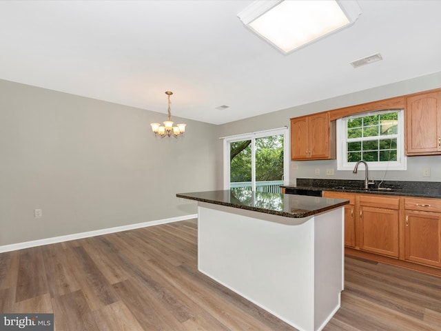 kitchen with pendant lighting, wood-type flooring, sink, and a center island