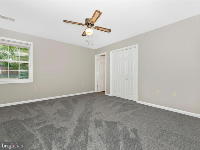 unfurnished bedroom with ceiling fan and dark colored carpet