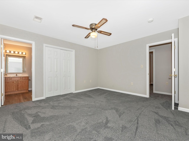 unfurnished bedroom with ensuite bathroom, ceiling fan, a closet, and dark carpet