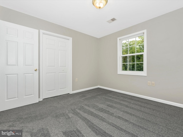 unfurnished bedroom with dark colored carpet