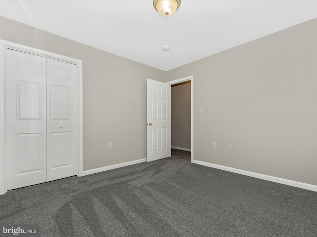 unfurnished bedroom featuring dark carpet and a closet