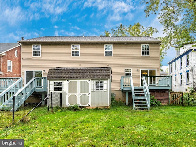 rear view of house with a wooden deck, a lawn, and a shed