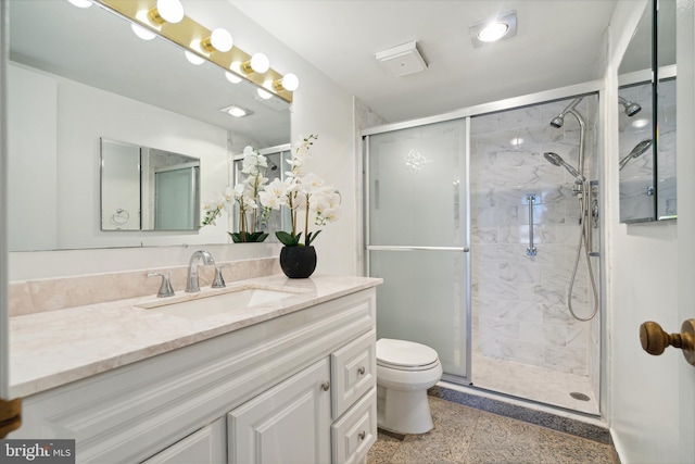 bathroom with vanity, toilet, and a shower with door