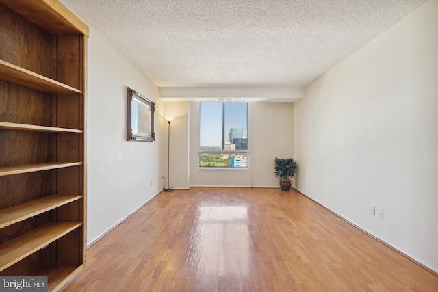 empty room with a textured ceiling and light hardwood / wood-style floors