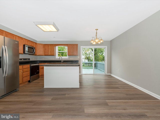 kitchen with a kitchen island, dark hardwood / wood-style floors, stainless steel appliances, a notable chandelier, and decorative light fixtures