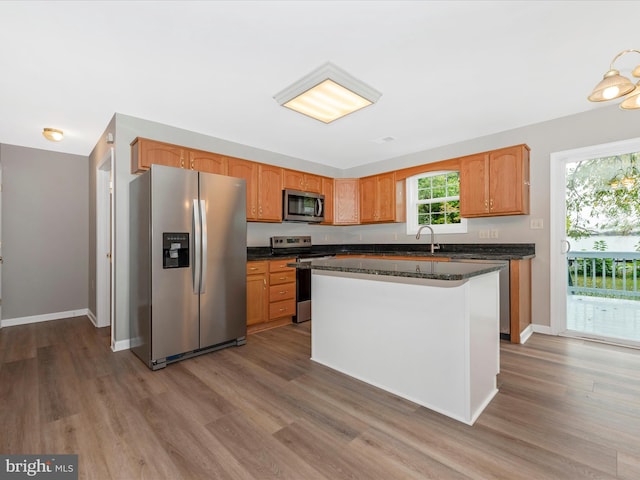 kitchen with a kitchen island, a healthy amount of sunlight, hardwood / wood-style floors, and stainless steel appliances