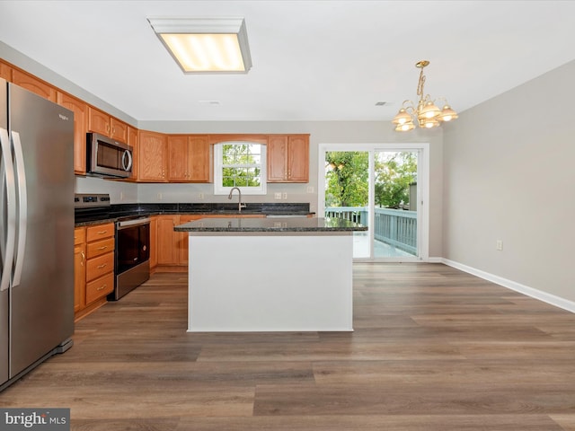 kitchen with decorative light fixtures, appliances with stainless steel finishes, dark hardwood / wood-style flooring, and a kitchen island