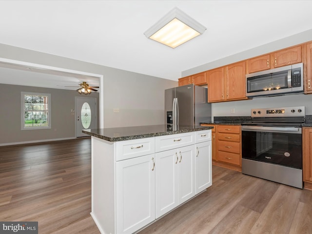 kitchen featuring ceiling fan, white cabinets, dark stone counters, light hardwood / wood-style flooring, and appliances with stainless steel finishes