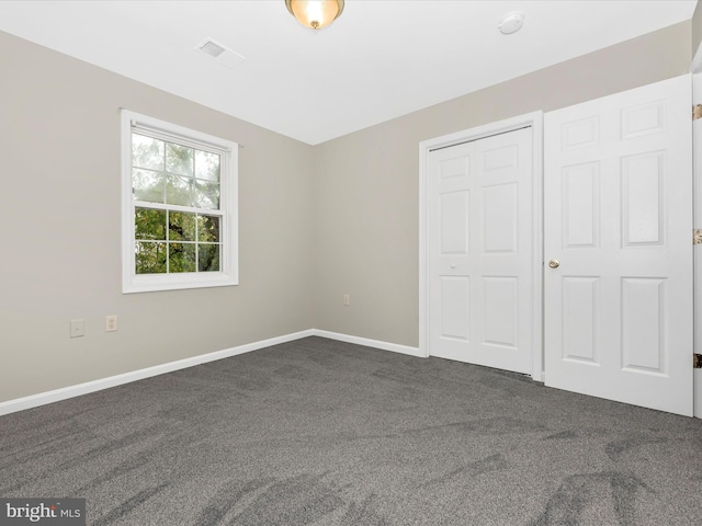 unfurnished bedroom featuring a closet and dark colored carpet