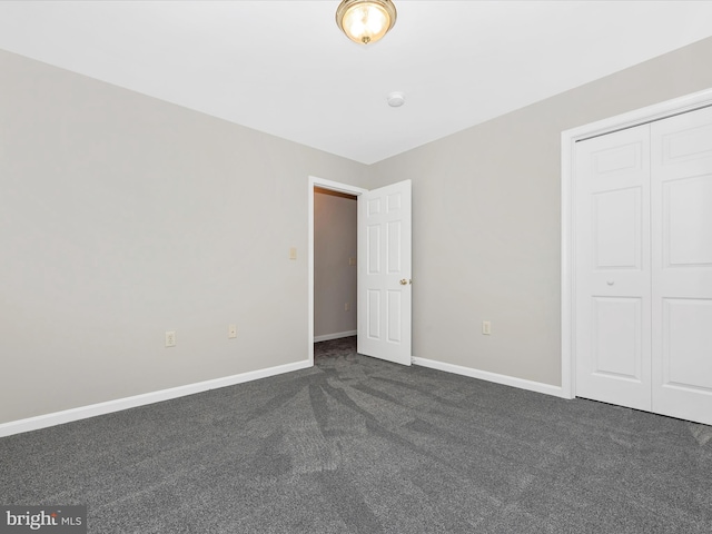 unfurnished bedroom with a closet and dark carpet