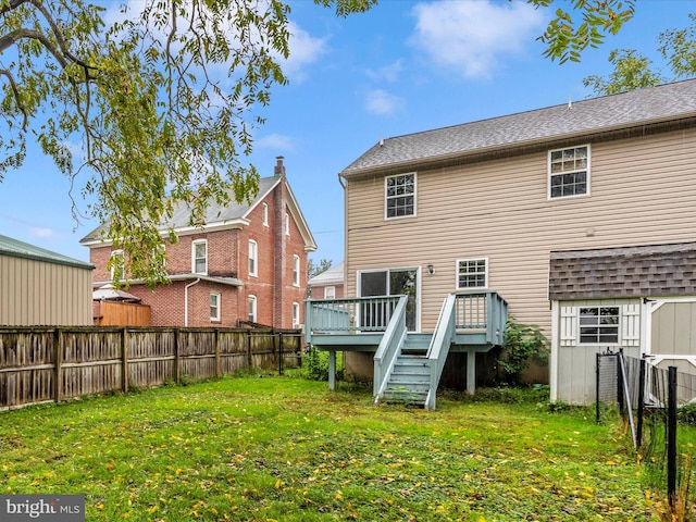 rear view of property featuring a yard and a wooden deck