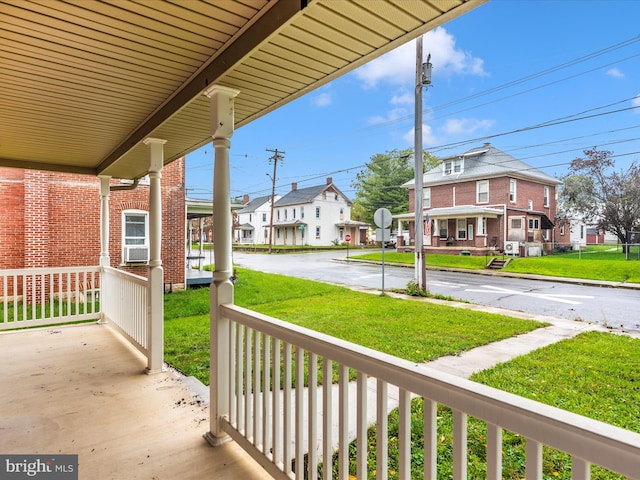 wooden terrace featuring a lawn and covered porch