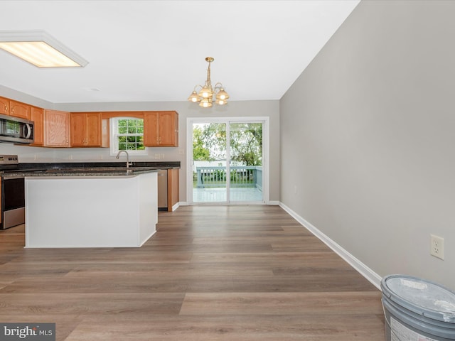 kitchen with pendant lighting, a notable chandelier, appliances with stainless steel finishes, and light hardwood / wood-style floors