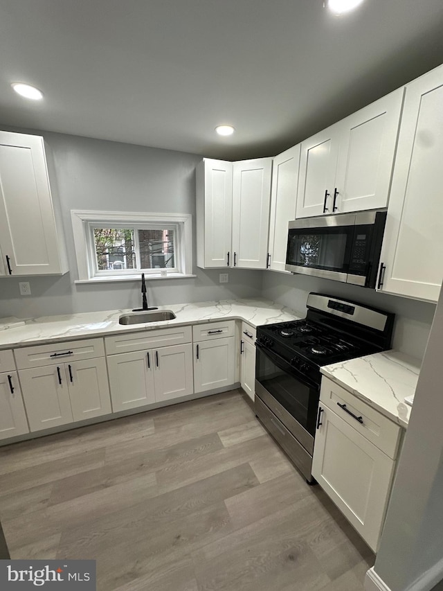 kitchen featuring white cabinetry, appliances with stainless steel finishes, light stone counters, and sink