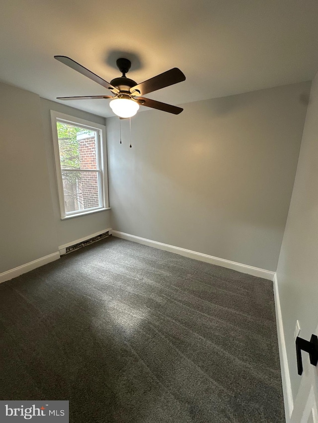 spare room featuring dark carpet, ceiling fan, and baseboard heating