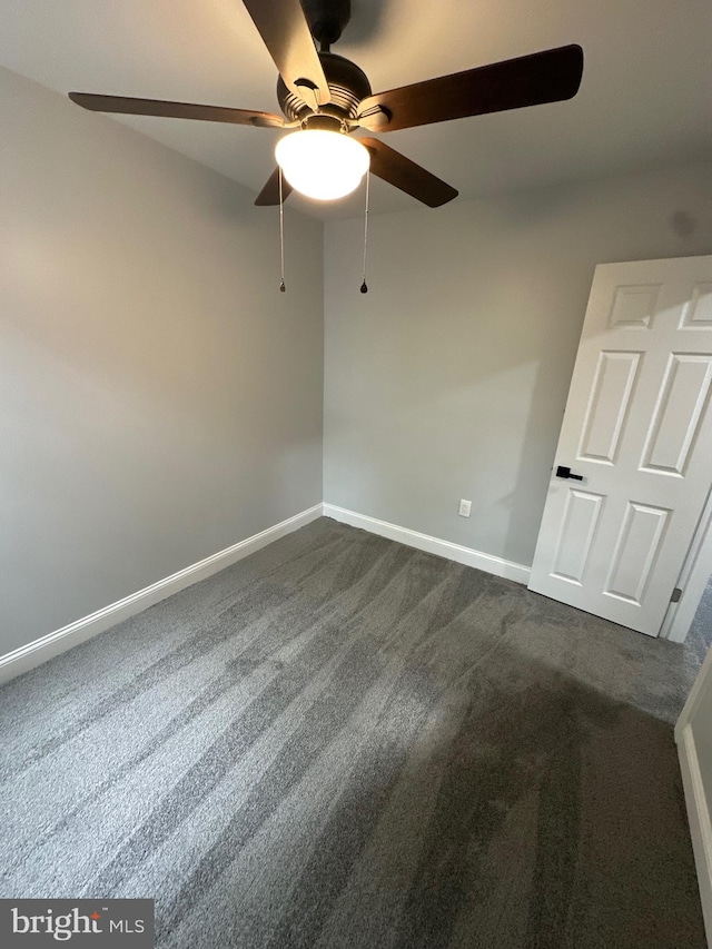 spare room featuring ceiling fan and dark carpet