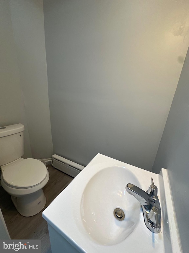 bathroom with wood-type flooring, a baseboard radiator, vanity, and toilet