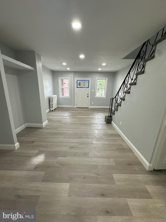 basement featuring light hardwood / wood-style flooring and radiator heating unit