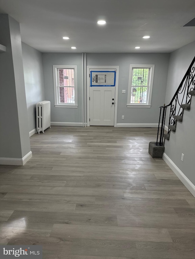 foyer with hardwood / wood-style floors, radiator heating unit, and a healthy amount of sunlight