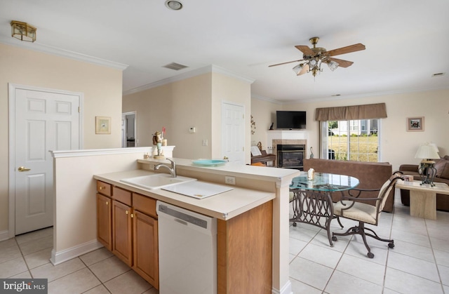 kitchen with a tile fireplace, light tile patterned flooring, sink, ornamental molding, and white dishwasher