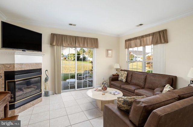 living room with ornamental molding, a tiled fireplace, light tile patterned floors, and a wealth of natural light