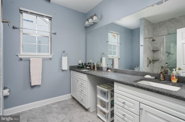 bathroom with a tile shower and vanity