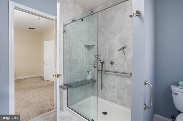 bathroom featuring toilet and a shower with door