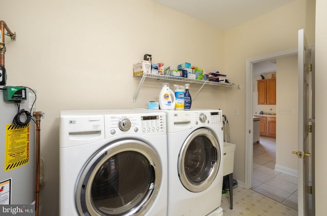 laundry area featuring water heater, light tile patterned floors, and washing machine and clothes dryer