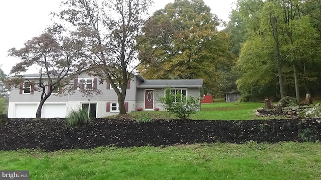 split level home featuring a garage and a front lawn