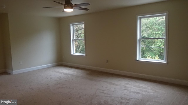 unfurnished room with ceiling fan, light colored carpet, and a wealth of natural light