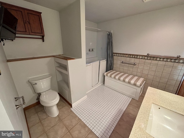 full bathroom with sink, shower / bathtub combination with curtain, tile patterned floors, toilet, and tile walls