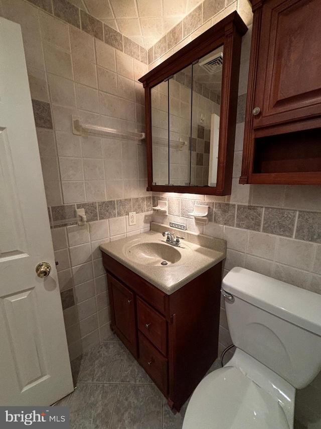 bathroom with tile walls, tile patterned floors, backsplash, vanity, and toilet