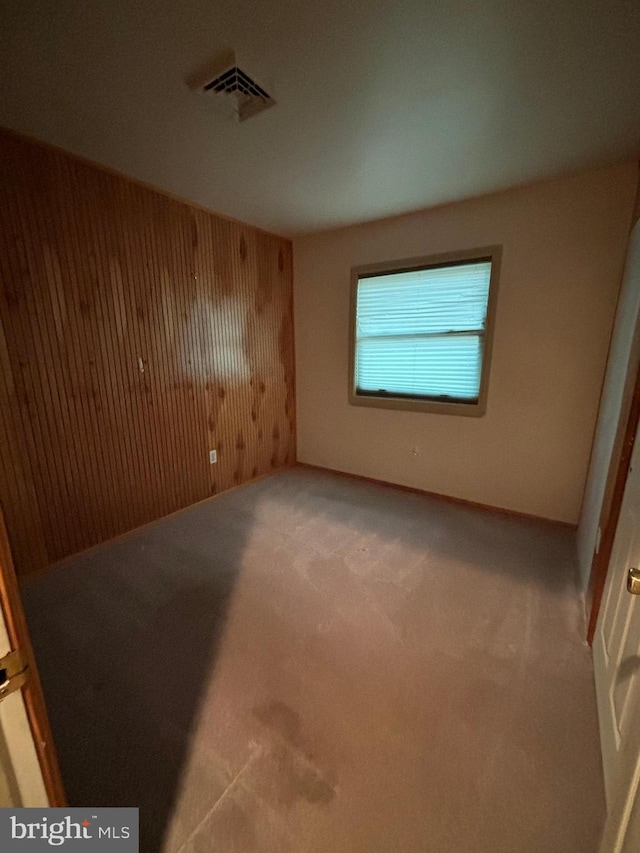 unfurnished room featuring wood walls and carpet floors