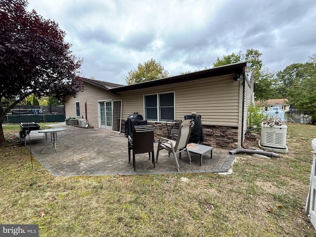 back of property with central air condition unit, a yard, and a patio area