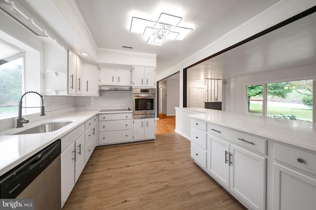 kitchen featuring tasteful backsplash, white cabinets, sink, light hardwood / wood-style flooring, and appliances with stainless steel finishes