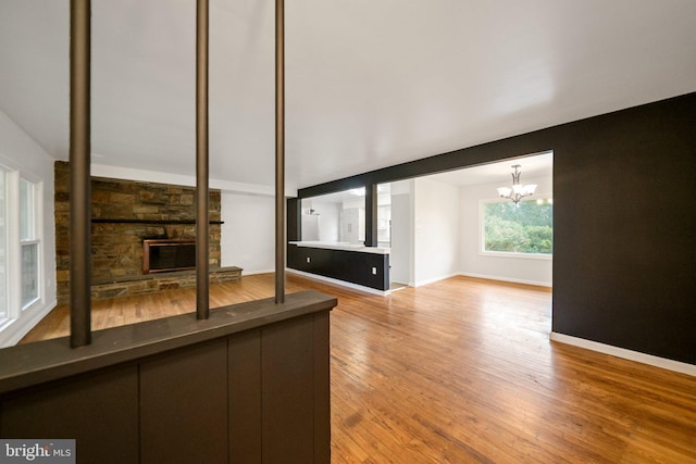 unfurnished living room featuring hardwood / wood-style flooring, a fireplace, and an inviting chandelier