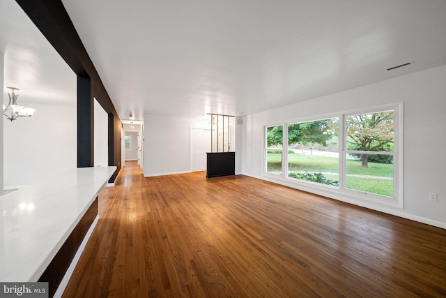 unfurnished living room with an inviting chandelier and hardwood / wood-style floors