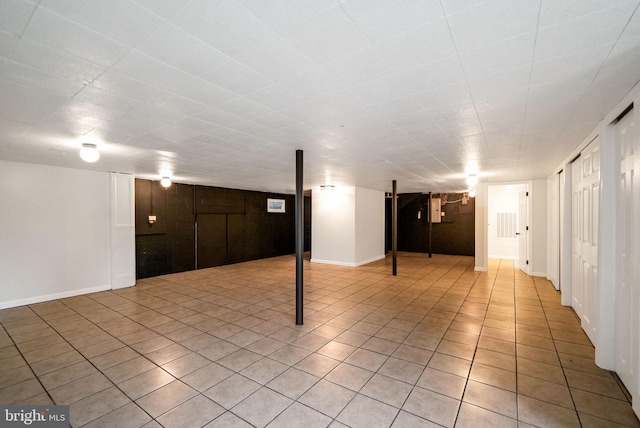 basement featuring wood walls and light tile patterned floors