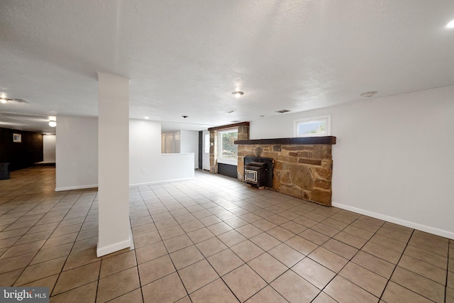 unfurnished living room with a textured ceiling, light tile patterned floors, and a wood stove