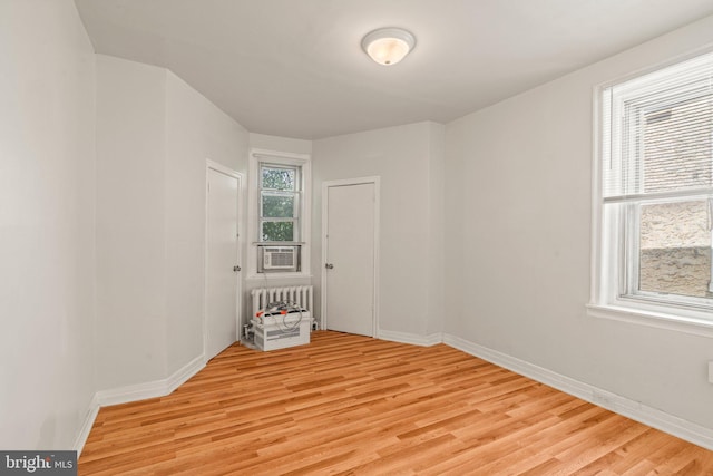 empty room featuring radiator and light hardwood / wood-style flooring