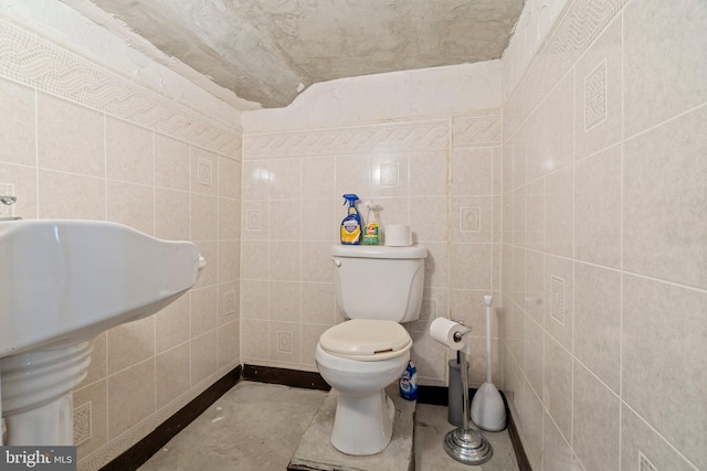 bathroom featuring tile walls and toilet