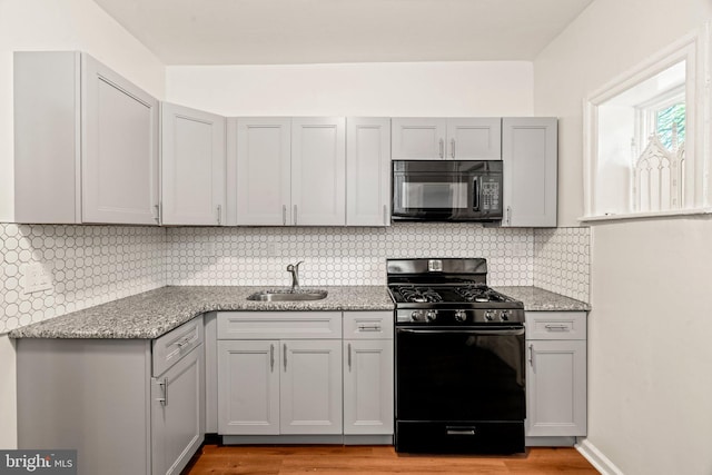 kitchen featuring light hardwood / wood-style flooring, black appliances, tasteful backsplash, and sink