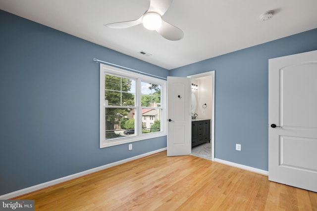 unfurnished bedroom with light wood-type flooring, connected bathroom, and ceiling fan