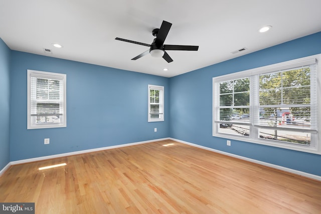 empty room with a healthy amount of sunlight, light hardwood / wood-style floors, and ceiling fan