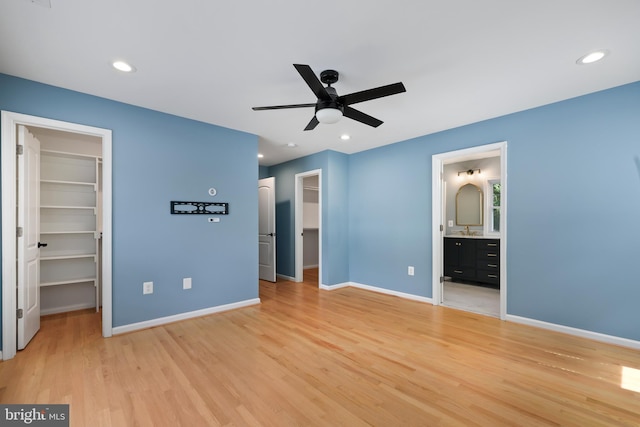 unfurnished bedroom featuring a spacious closet, light wood-type flooring, a closet, and ensuite bathroom